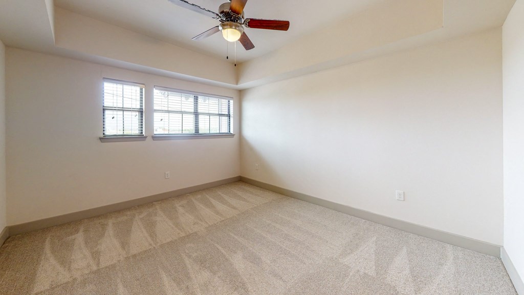the spacious living room with carpeting and a ceiling fan