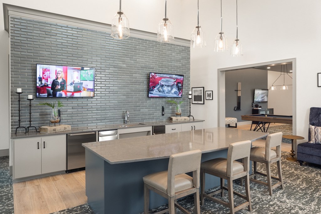a kitchen with a large island with chairs and a tv