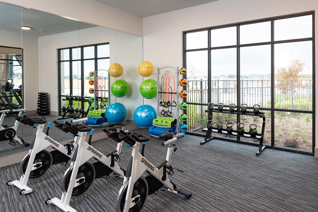 a spin class room in a fitness center with exercise bikes and weights