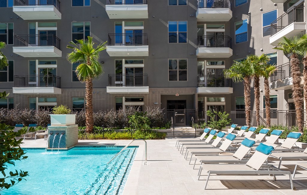 a swimming pool with lounge chairs in front of an apartment building