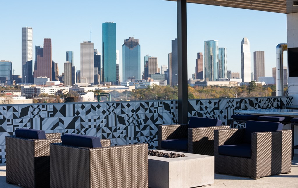 a view of the city skyline from a rooftop patio with tables and chairs