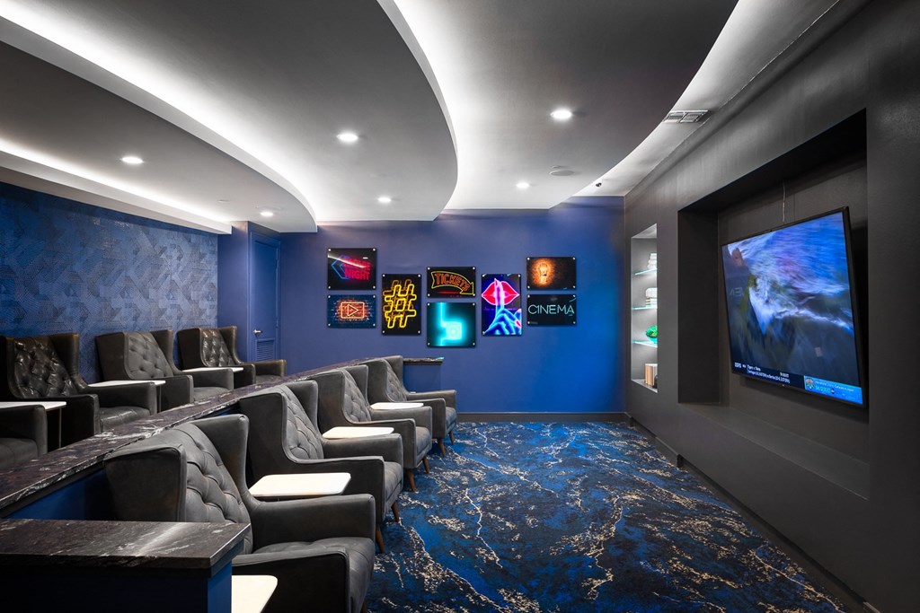 a home theater room with blue walls and chairs and a tv