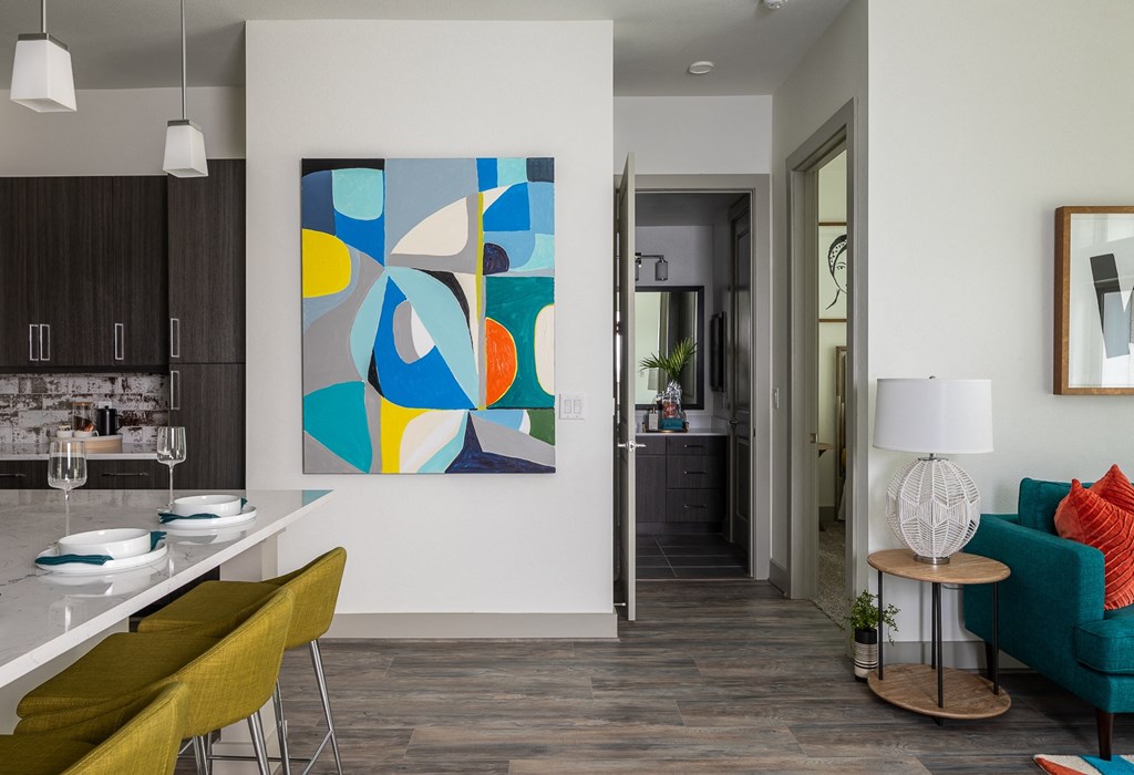 a living room and kitchen with a colorful painting on the wall