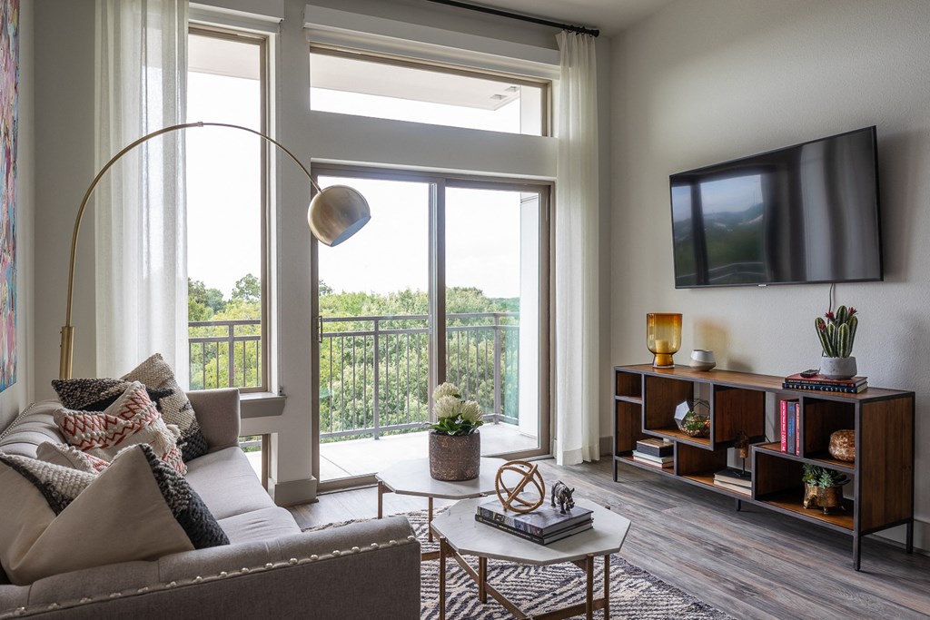 a living room with a couch and a tv and a balcony