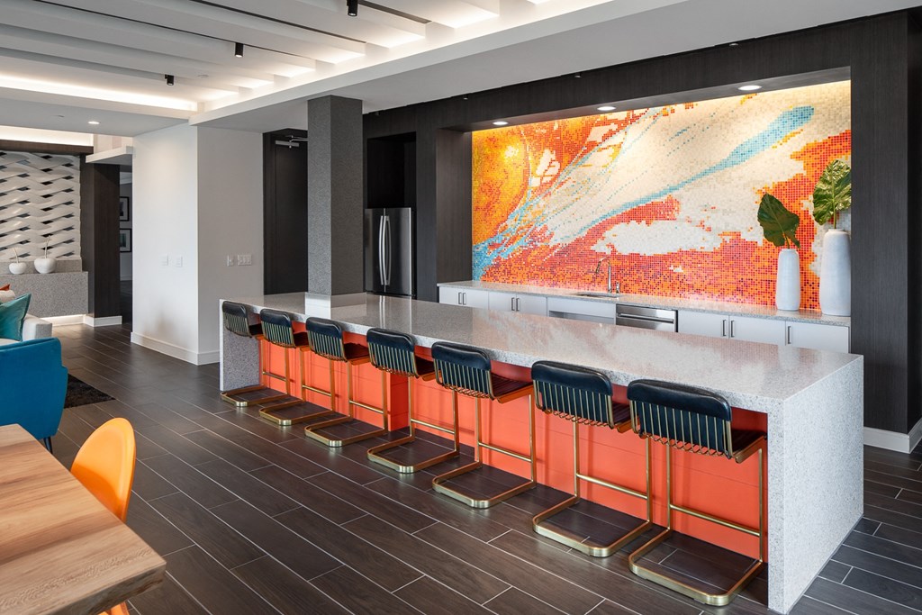 the lobby of a building with a marble counter and orange chairs