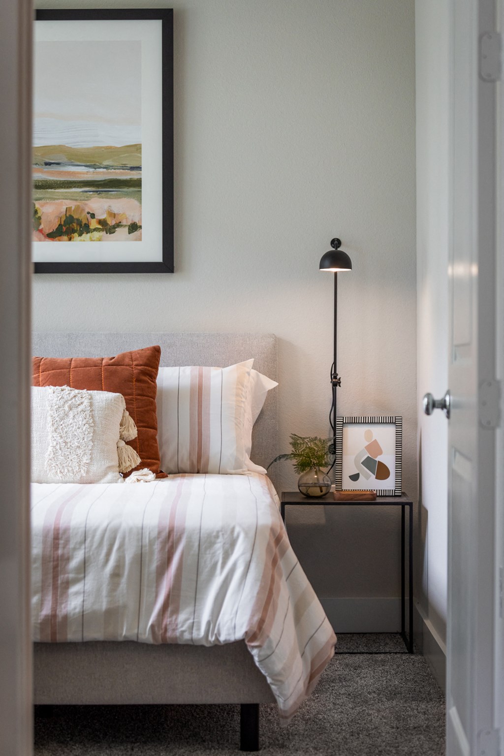a bedroom with a bed and a lamp and a painting on the wall