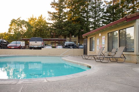 A pool with chairs and a building in the background.