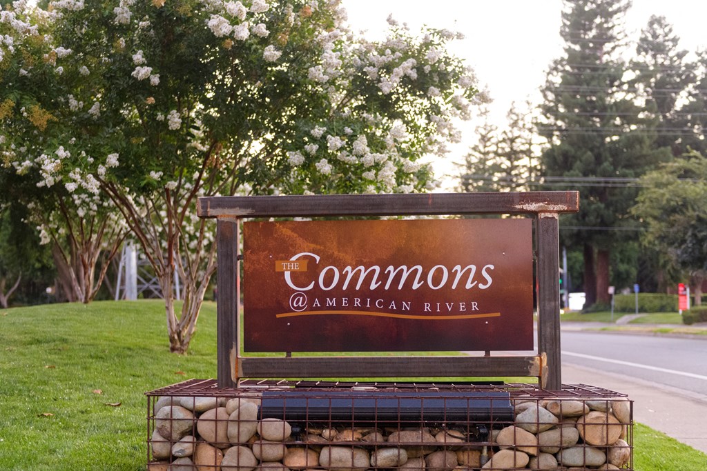 A sign that says "Commons @ American River" is displayed on a stone wall.