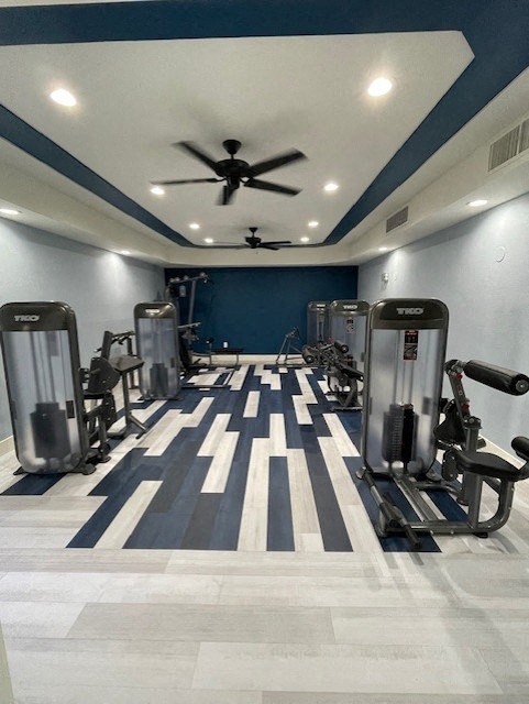 A gym with a variety of equipment including treadmills, weights, and a ceiling fan.