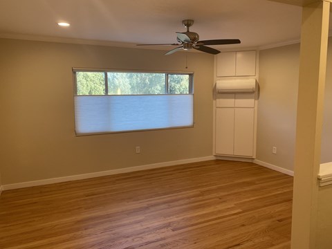 an empty living room with a window and a ceiling fan