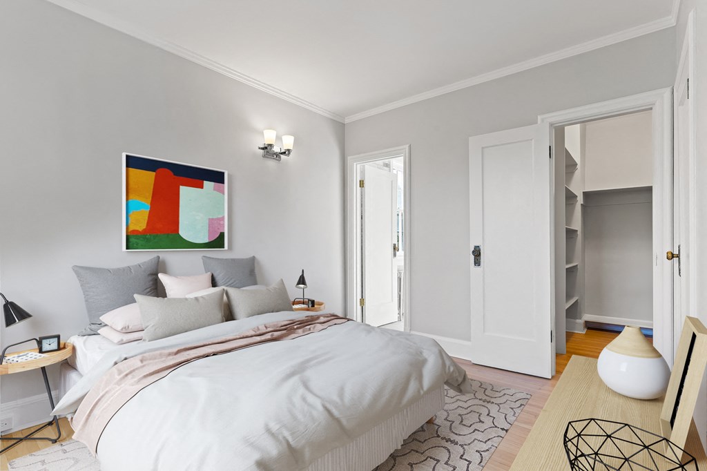 A bedroom with a large bed and a painting on the wall.