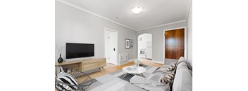 A living room with a grey couch and a black television.