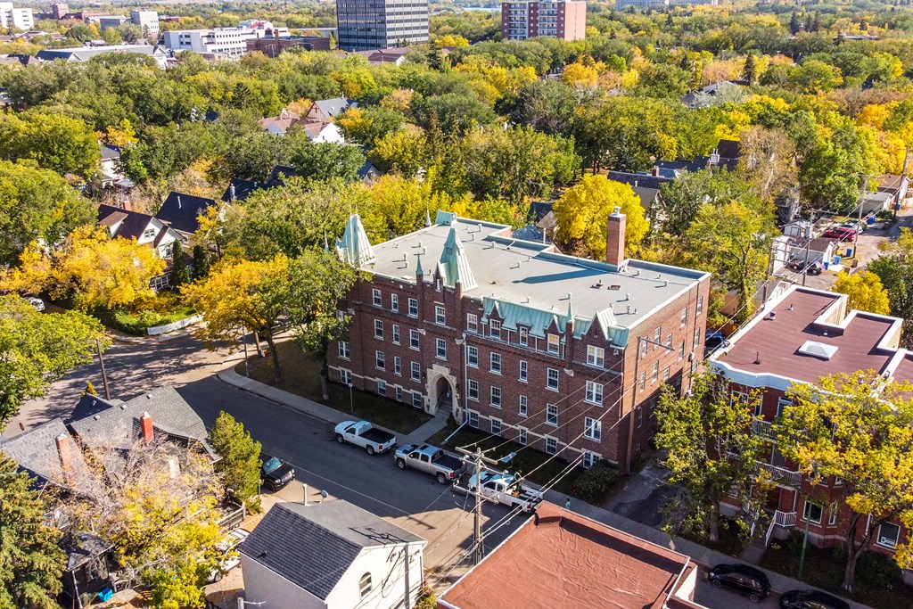 A large red brick building with a green roof sits in the middle of a street.