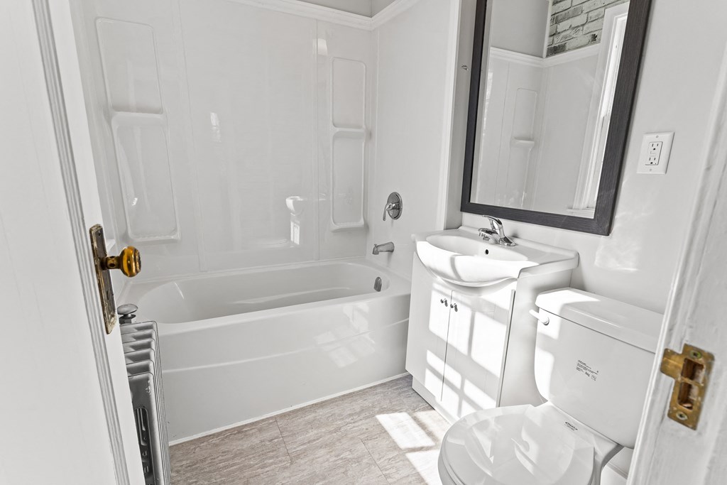 A white bathroom with a tub, toilet, and sink.