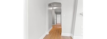 A long hallway with wood floors and white walls.