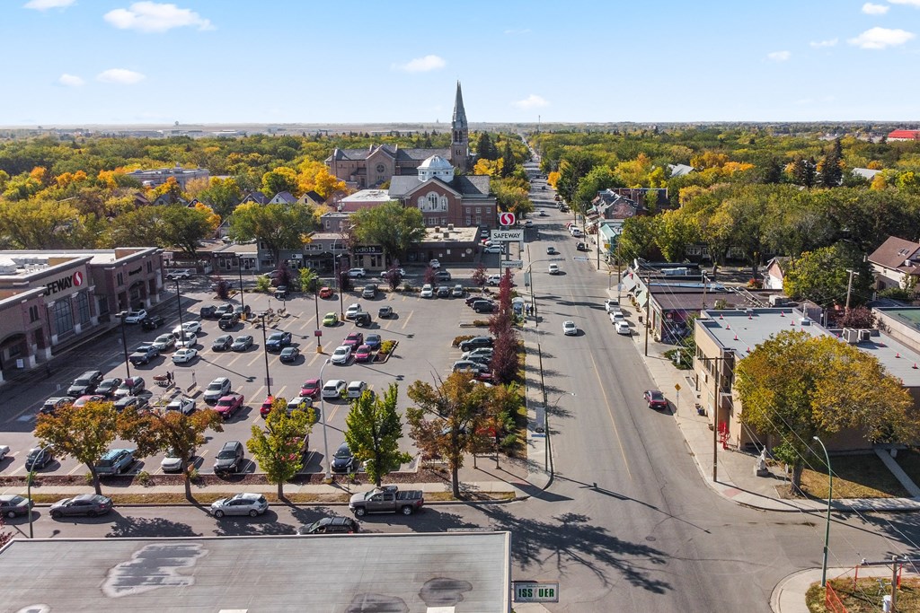 A street view of a town with a church spire in the distance.