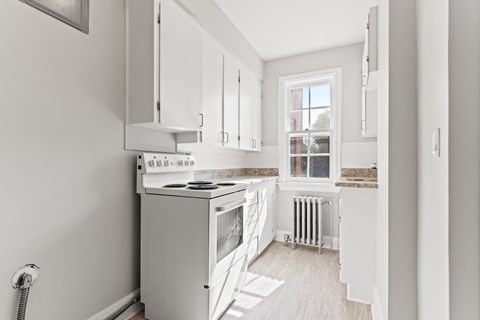 A kitchen with white cabinets and a stove top oven.