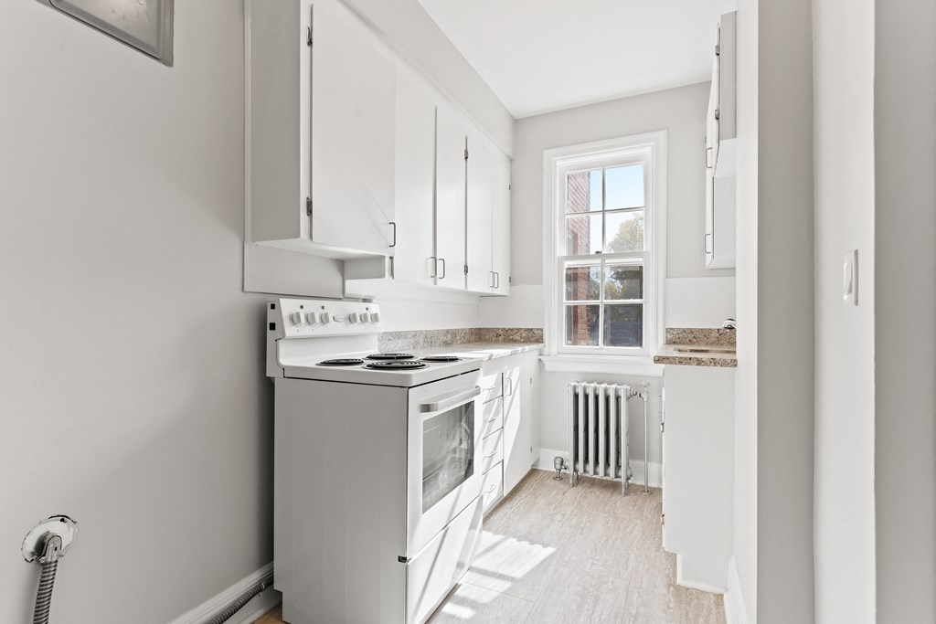 A kitchen with white cabinets and a stove top oven.