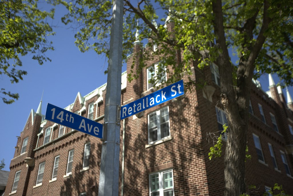 A street sign for 14th Ave and Retalack St is shown in front of a brick building.