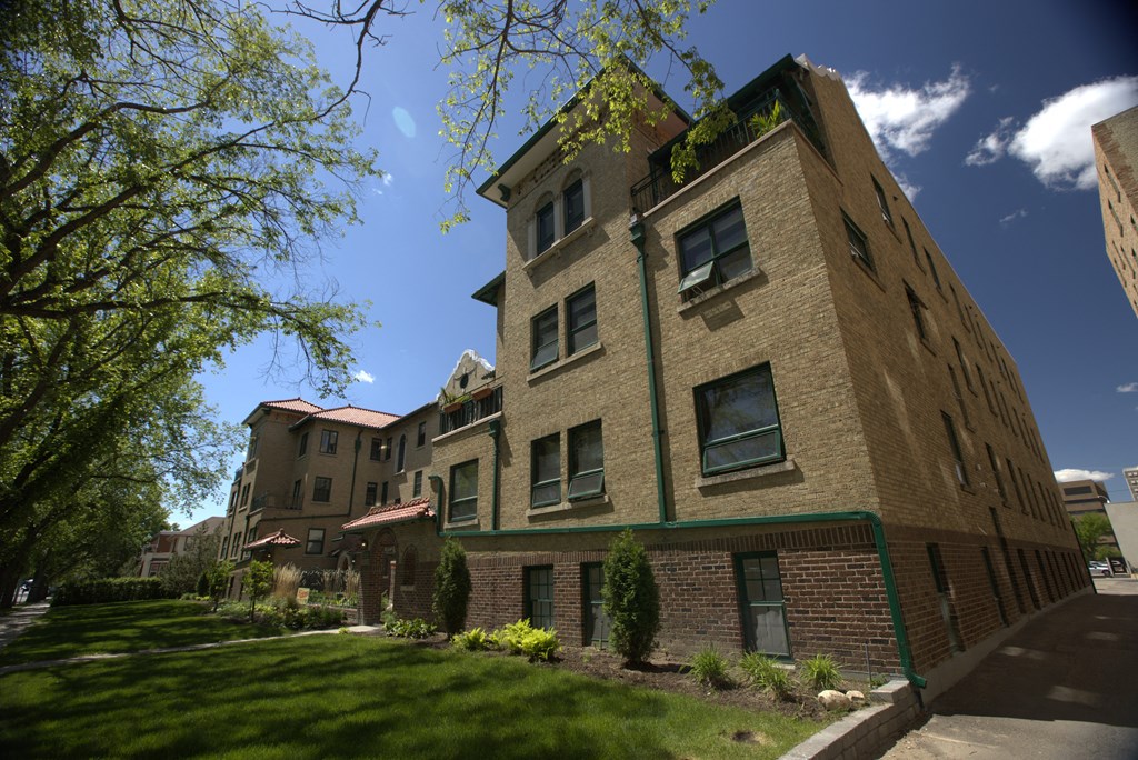 A tall building with a green trim around the windows and a red roof.