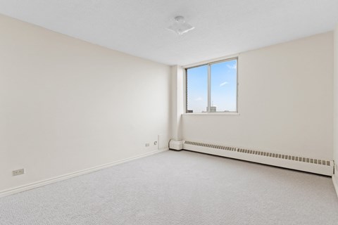A white room with a window and a radiator on the wall.