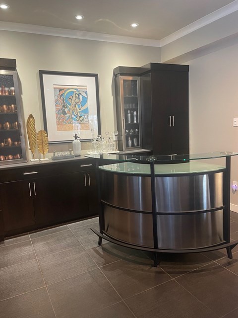 A modern kitchen with a curved glass island and dark wood cabinets.
