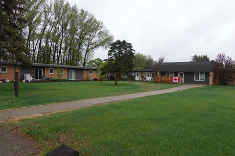 A grassy area in front of a building with a red sign on it.