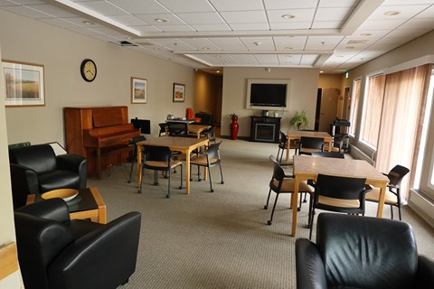 A conference room with a piano, chairs, and a television.