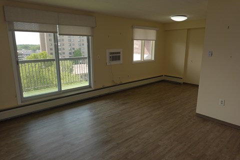 A room with a window overlooking a balcony with a railing.