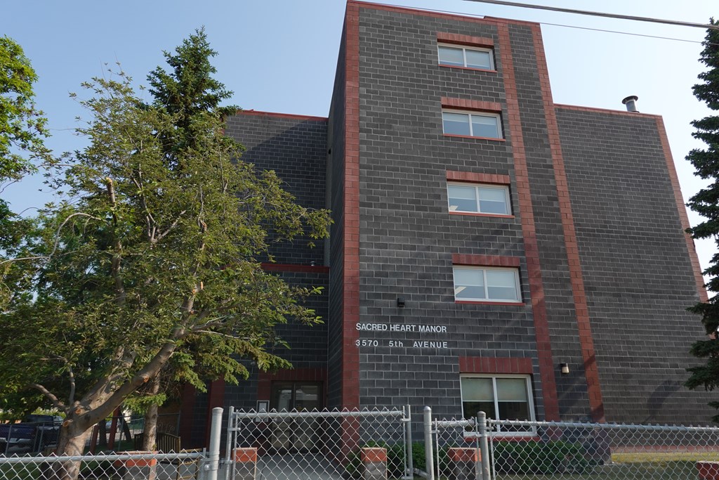 A brick building with a sign that says Sacred Heart Manor.