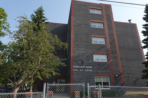 A brick building with a sign that says Sacred Heart Manor.