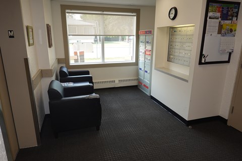 A waiting room with two chairs and a wall clock.