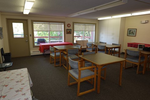 A room with tables and chairs and a window.