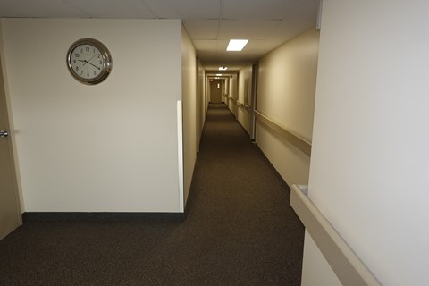 A long hallway with a clock on the wall.