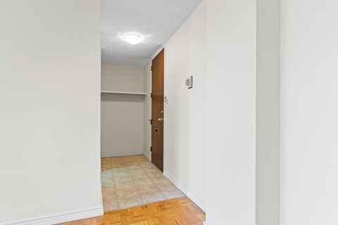 A hallway with a door and a light switch on the wall.