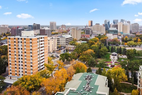 A cityscape with a large building in the foreground and a park with a green roof.