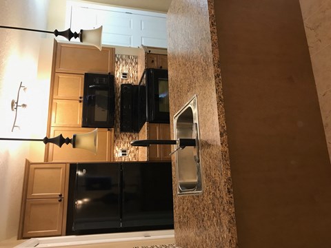A kitchen with a black refrigerator and a black stove top oven.