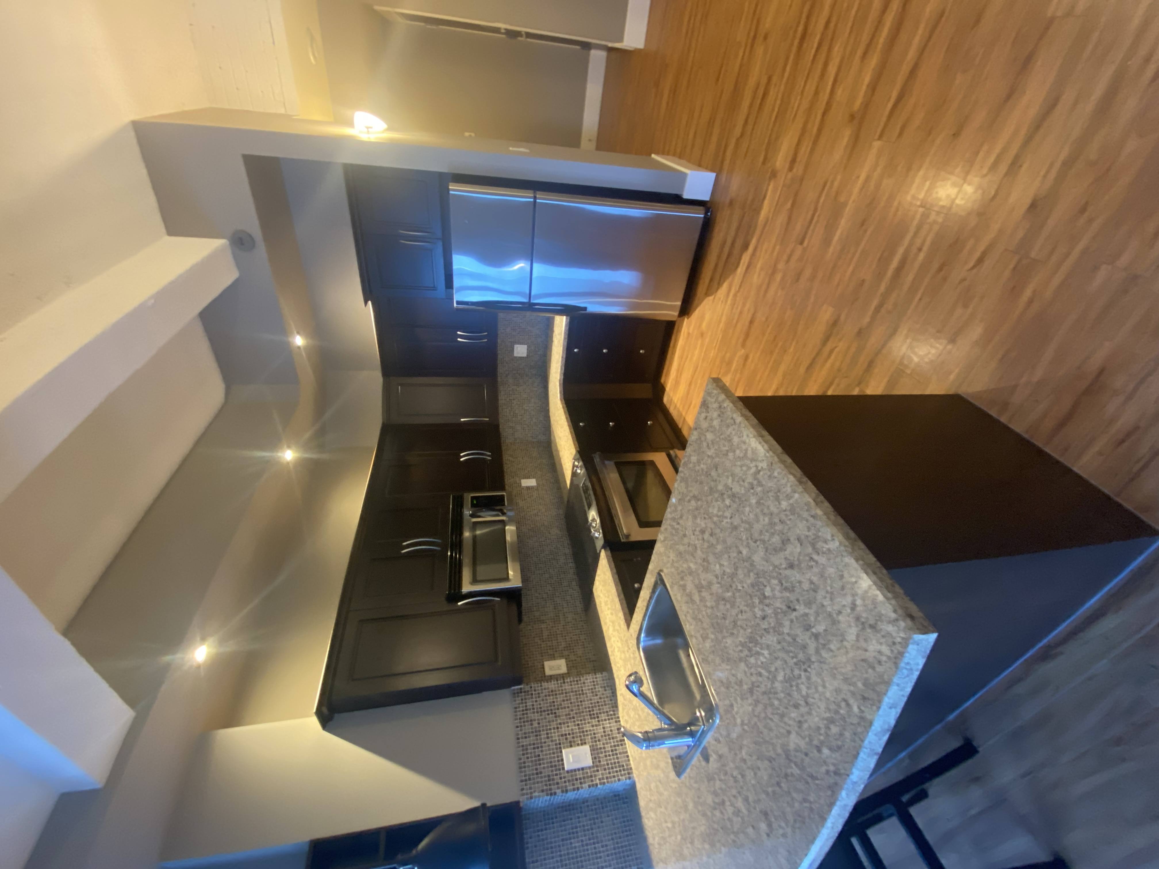A modern kitchen with a wooden counter and stainless steel appliances.