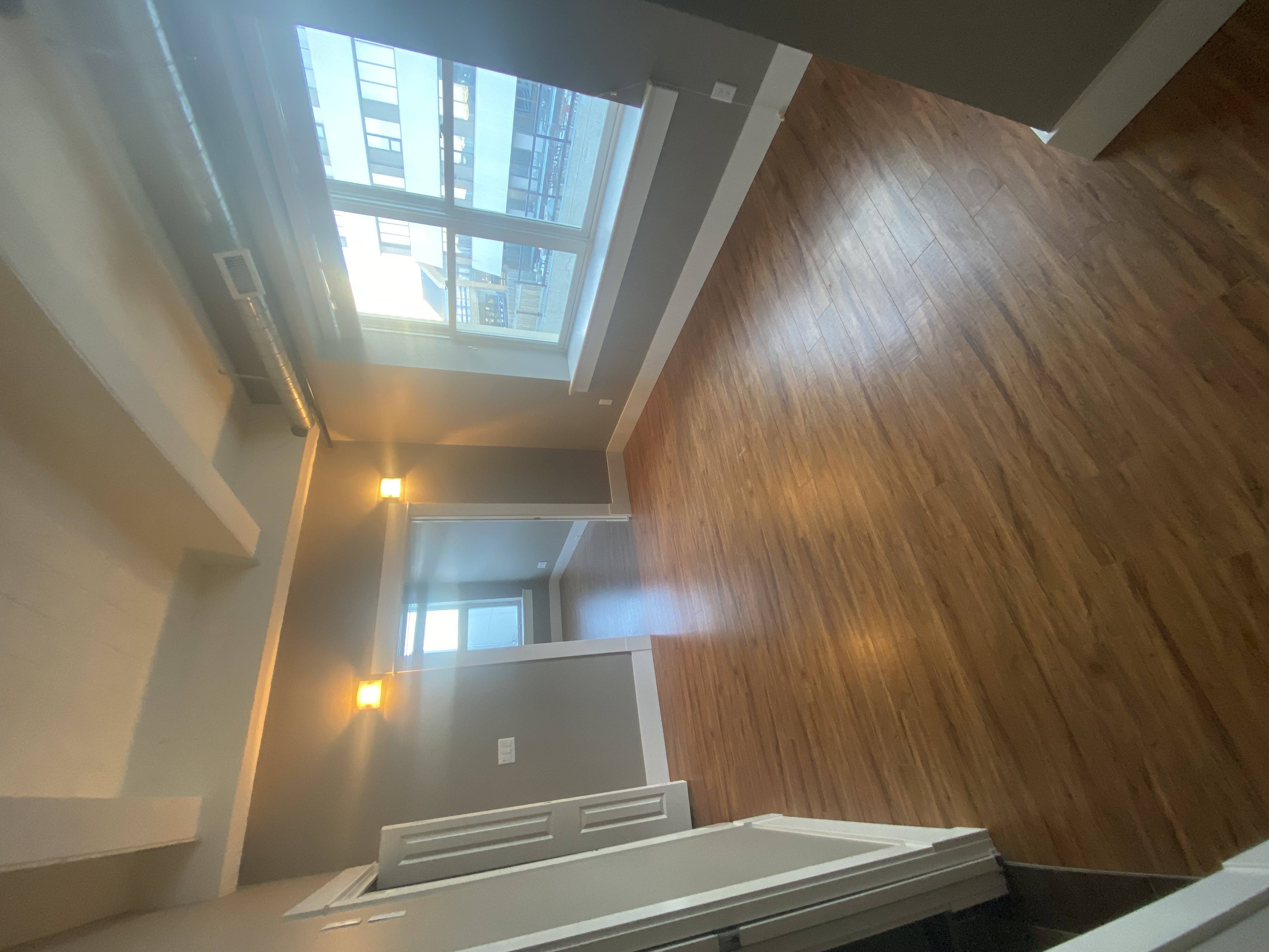 A wooden staircase leads up to a skylight.