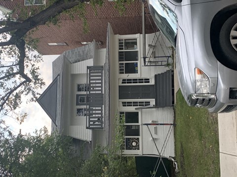 A car is parked in front of a building with a tree in the foreground.
