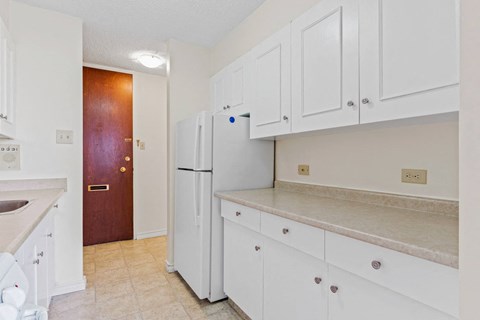 A kitchen with white cabinets and a white fridge.