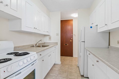 A kitchen with white cabinets and a white stove.