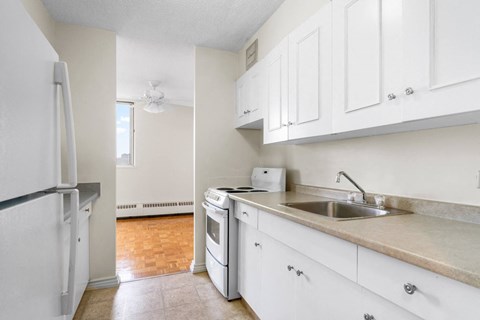 A kitchen with white cabinets and a white fridge.