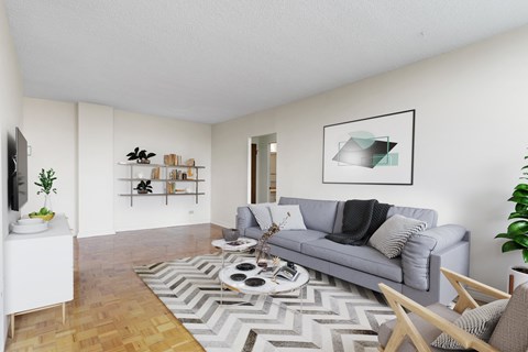 A living room with a grey couch, a coffee table, and a TV on the wall.