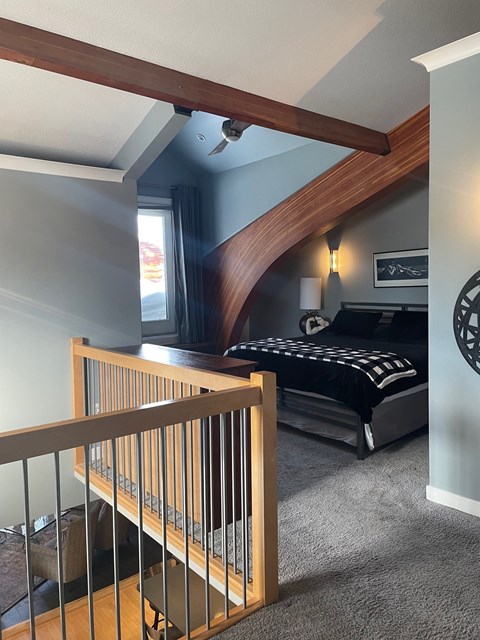 A bedroom with a bed, a window, and a staircase.
