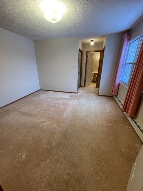 A room with a carpeted floor and a doorway leading to another room.