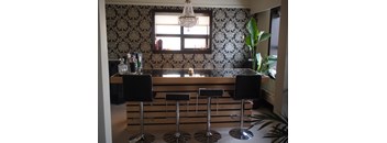 A bar with three stools and a chandelier.