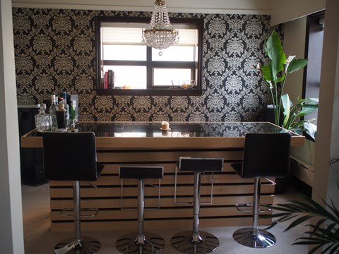 A bar with three stools and a chandelier.