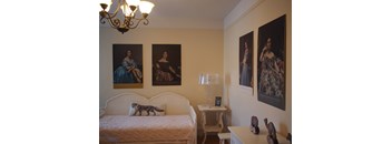 A bedroom with a bed, nightstand, and three framed pictures on the wall.