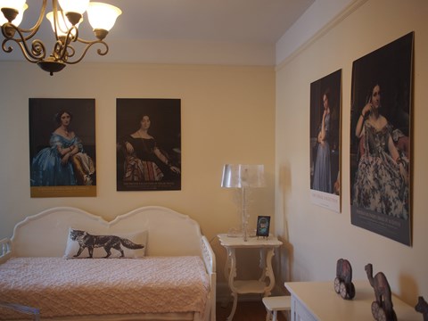 A bedroom with a bed, nightstand, and three framed pictures on the wall.